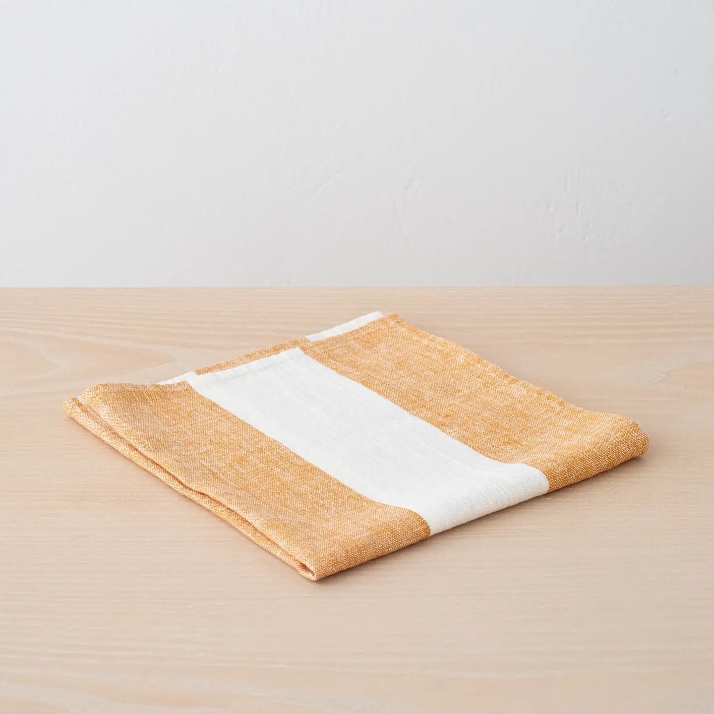 Folded fabric with a white stripe on a wooden surface