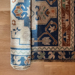 vintage area rug with navy, brown, tan and cream colored pattern