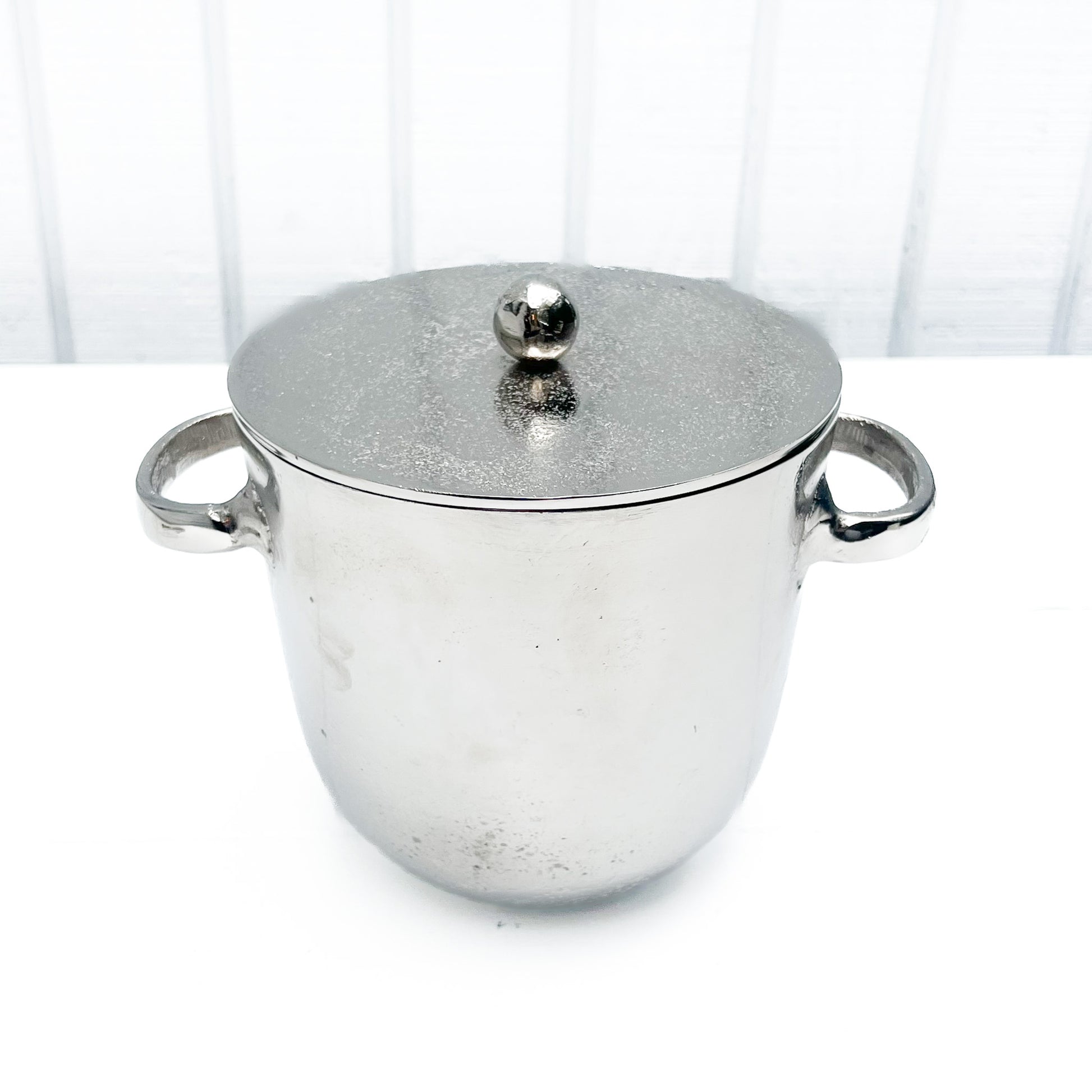 silver metal ice bucket with two handles and a lid
