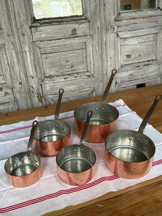 Set of copper pots on a wooden table with a rustic background
