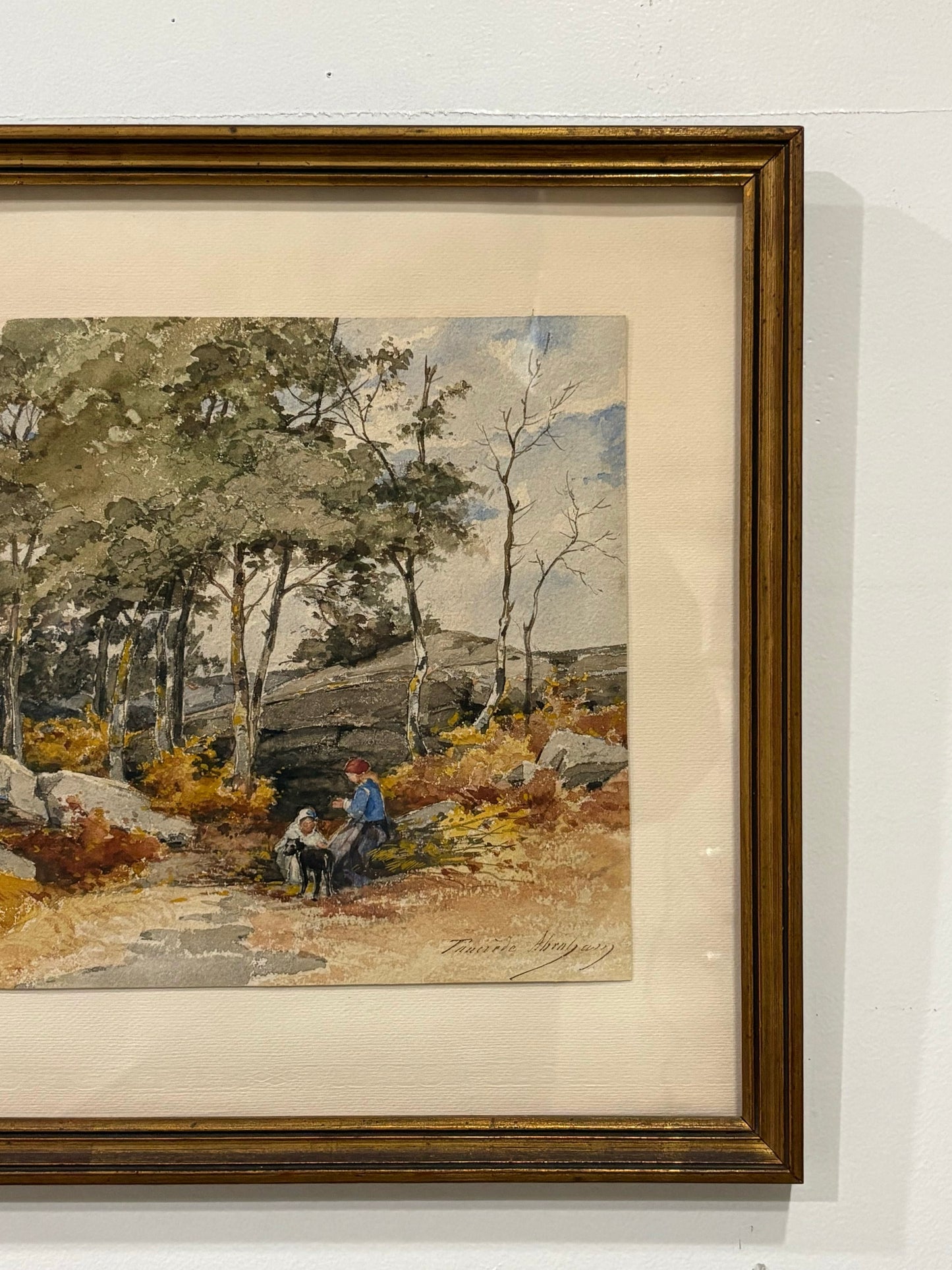 Framed artwork of a landscape with trees and people sitting on a rock.
