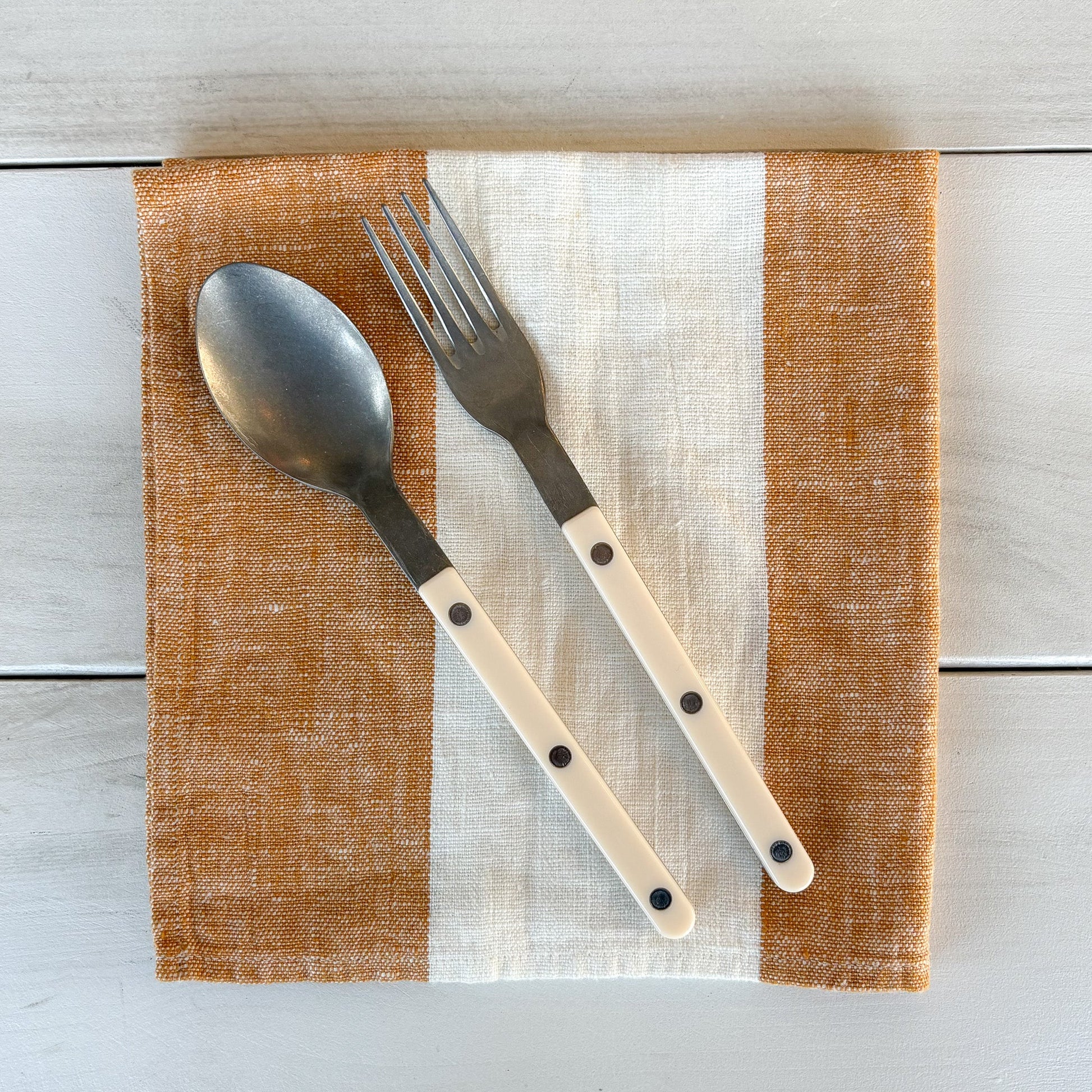 Fork and spoon on a striped placemat with a wooden background