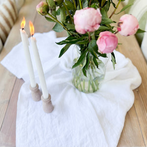 linen white table cloth on wood table with pink flowers and taper candles