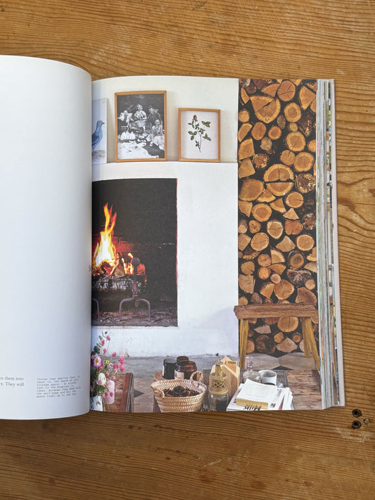 Open book on a wooden surface with images of a fireplace and stacked logs.