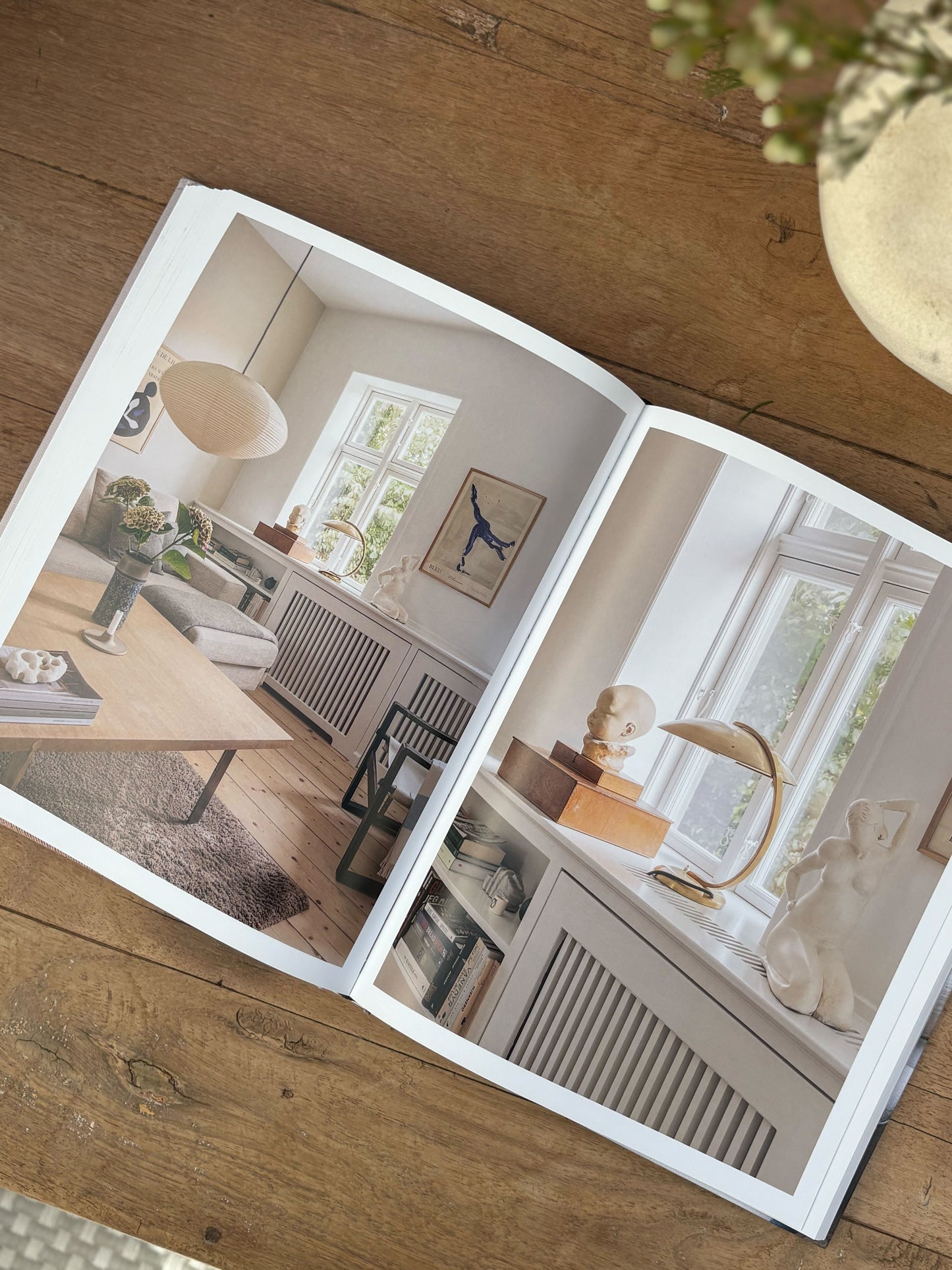Open book showing interior design images on a wooden surface