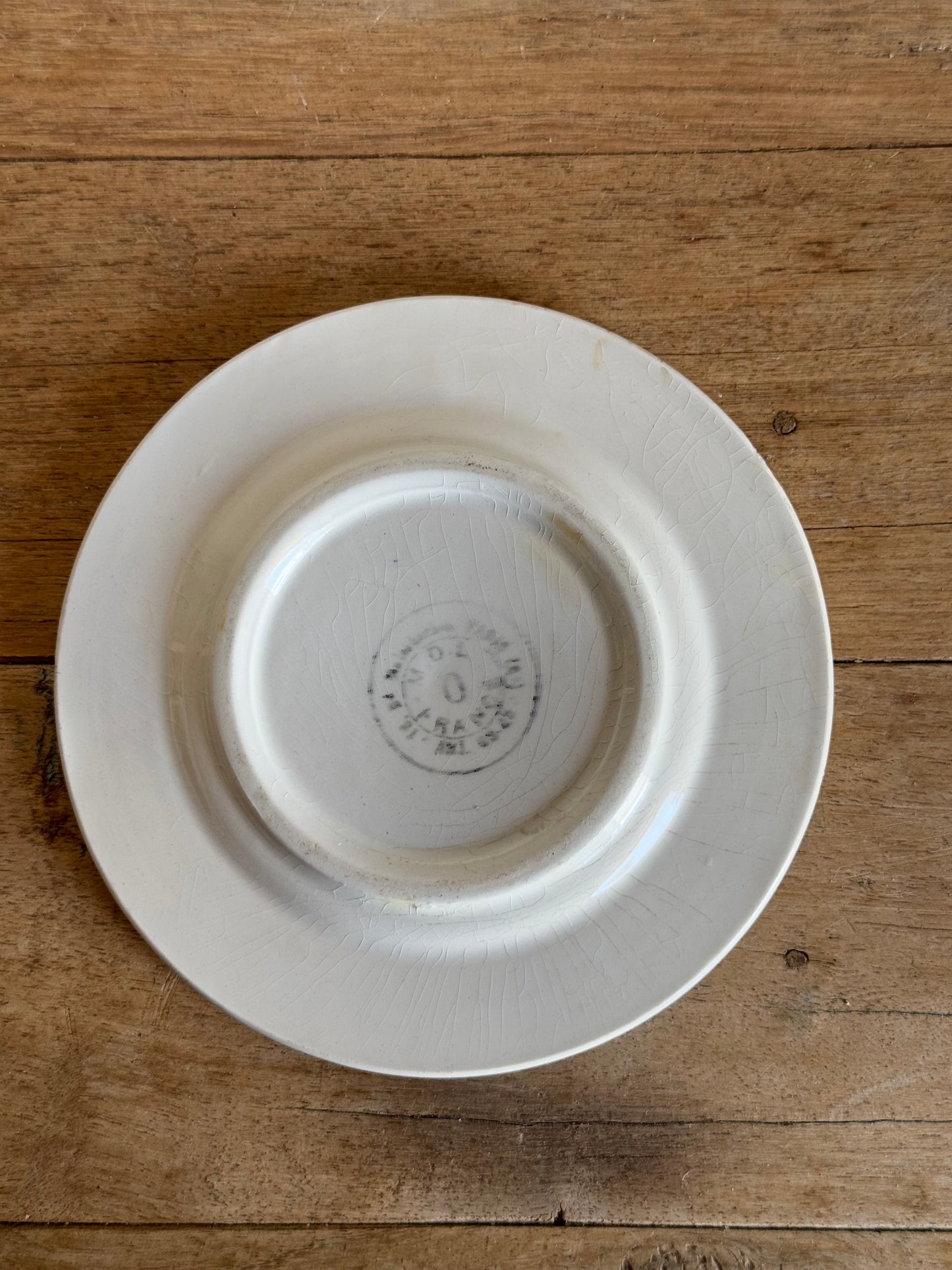 White ceramic plate with a visible brand logo on a wooden surface