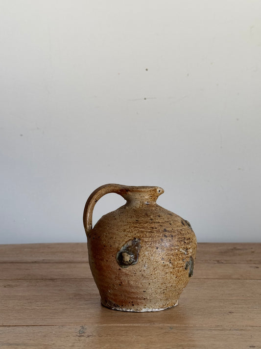 Brown ceramic mug with a handle on a wooden surface