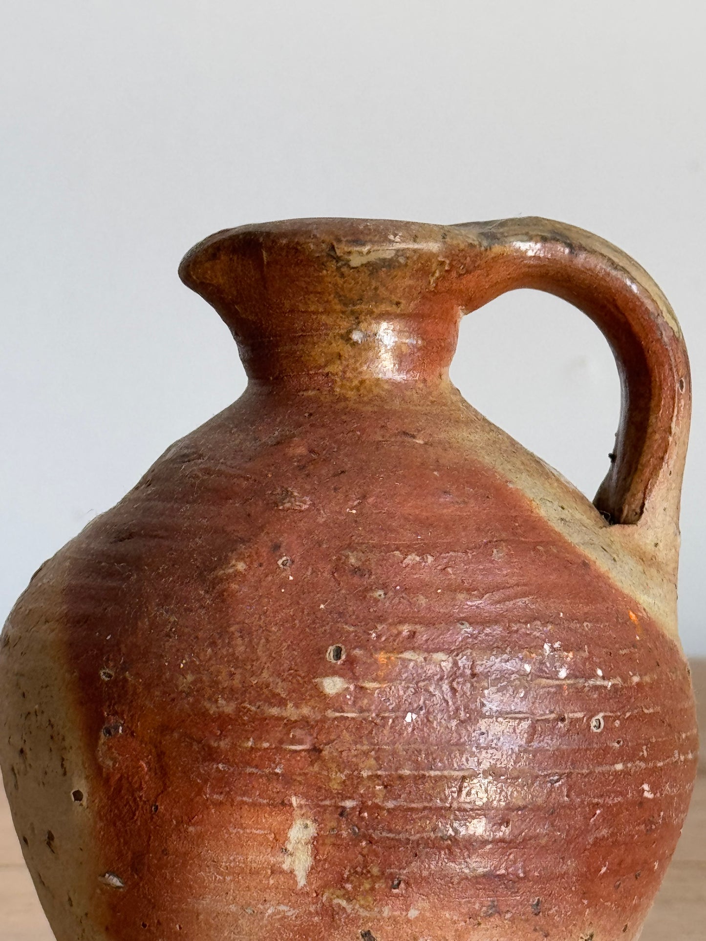 Brown ceramic jar with a handle on a white background