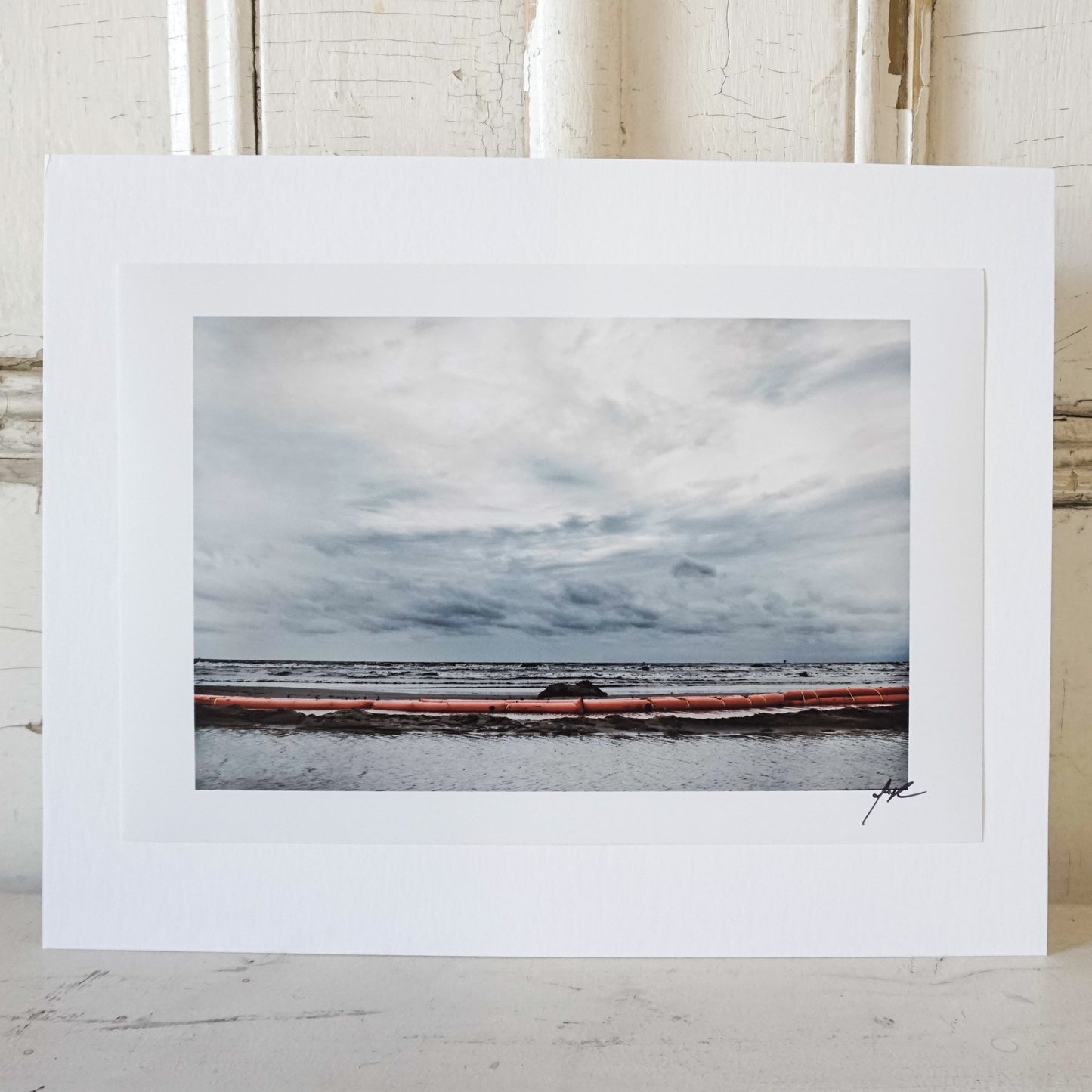 ocean with gray clouds and red barrier at shore line Edit alt text