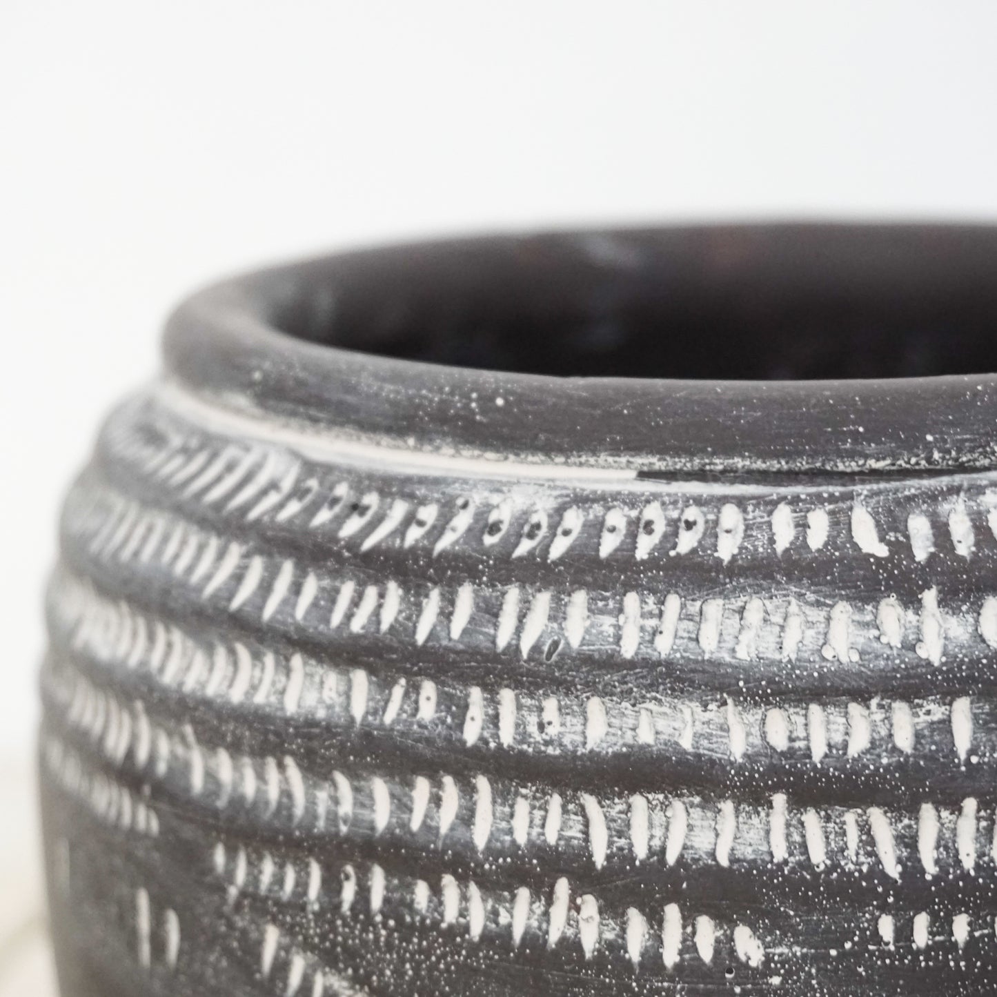 Black ceramic pot with white markings around top