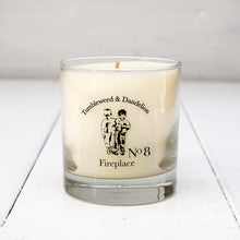 Load image into Gallery viewer, Clear glass candle with Tumbleweed and Dandelion logo, earthy fireplace scent