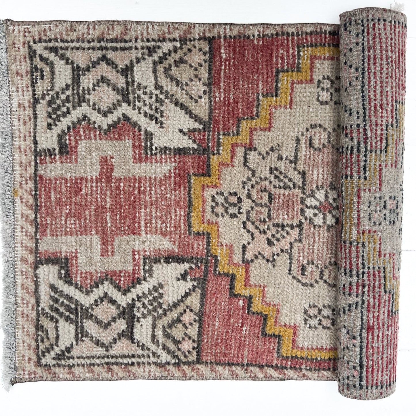 brick red, cream, gold, tan and black colored small Turkish rug
