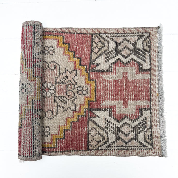 brick red, cream, gold, tan and black colored small Turkish rug