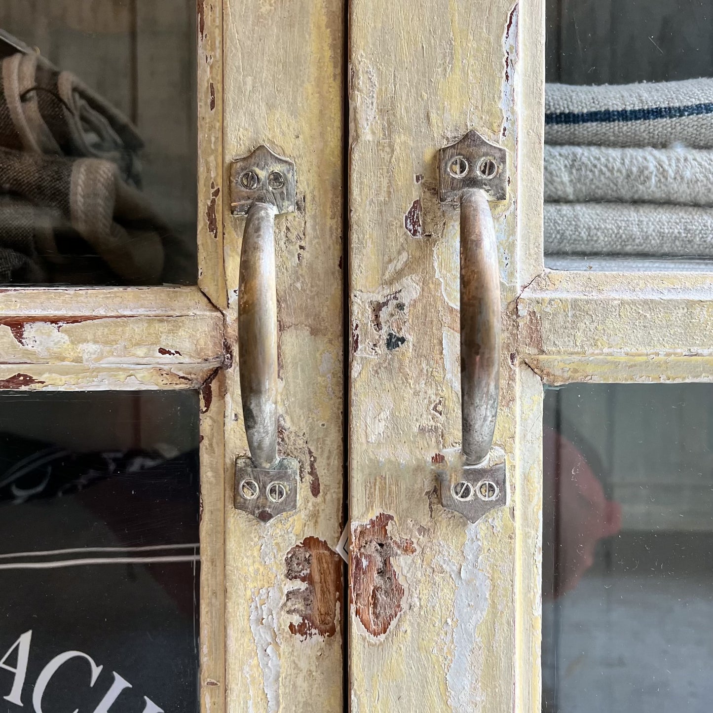 rustic hutch of old wood with distressed butter yellow paint finish, glass doors on top and bottom