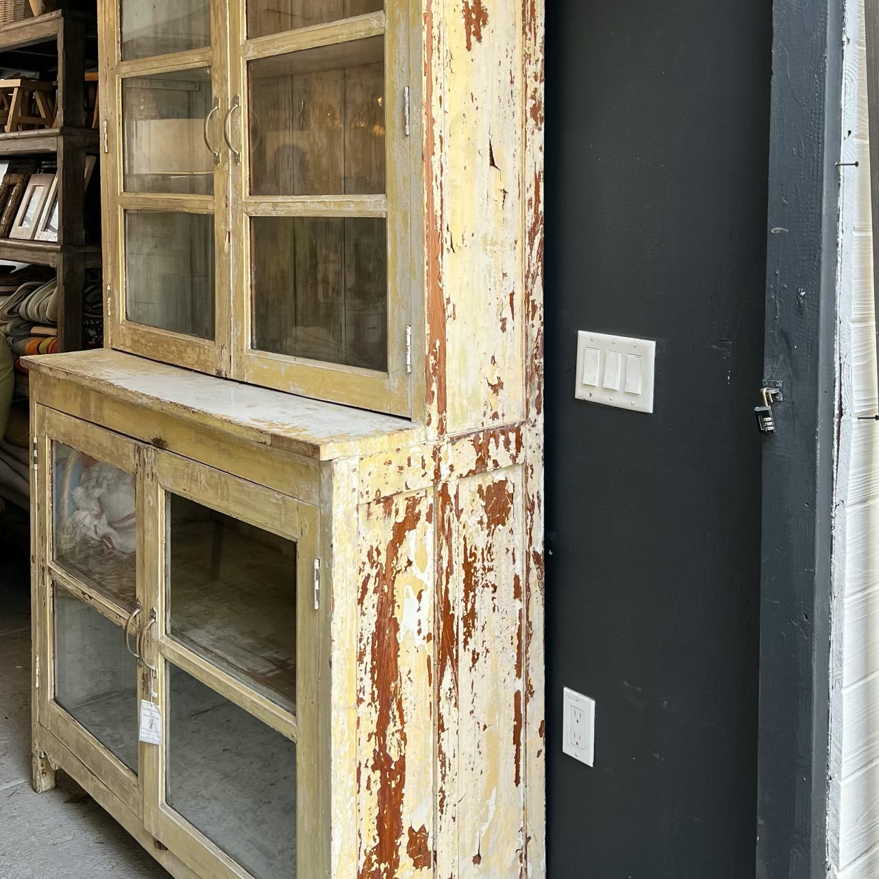rustic hutch of old wood with distressed butter yellow paint finish, glass doors on top and bottom