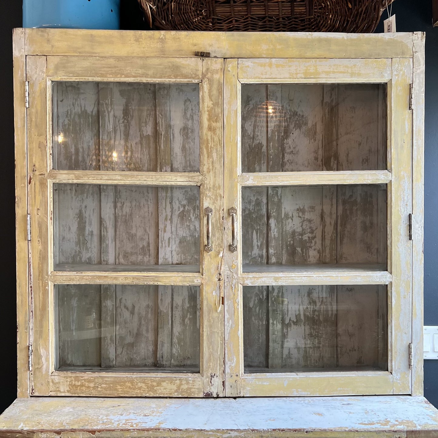 rustic hutch of old wood with distressed butter yellow paint finish, glass doors on top and bottom