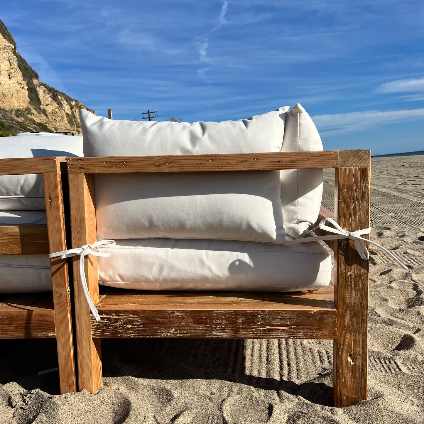 sectional sofa made of repurposed wood, off white cushions with outdoor fabric, medium brown wood color