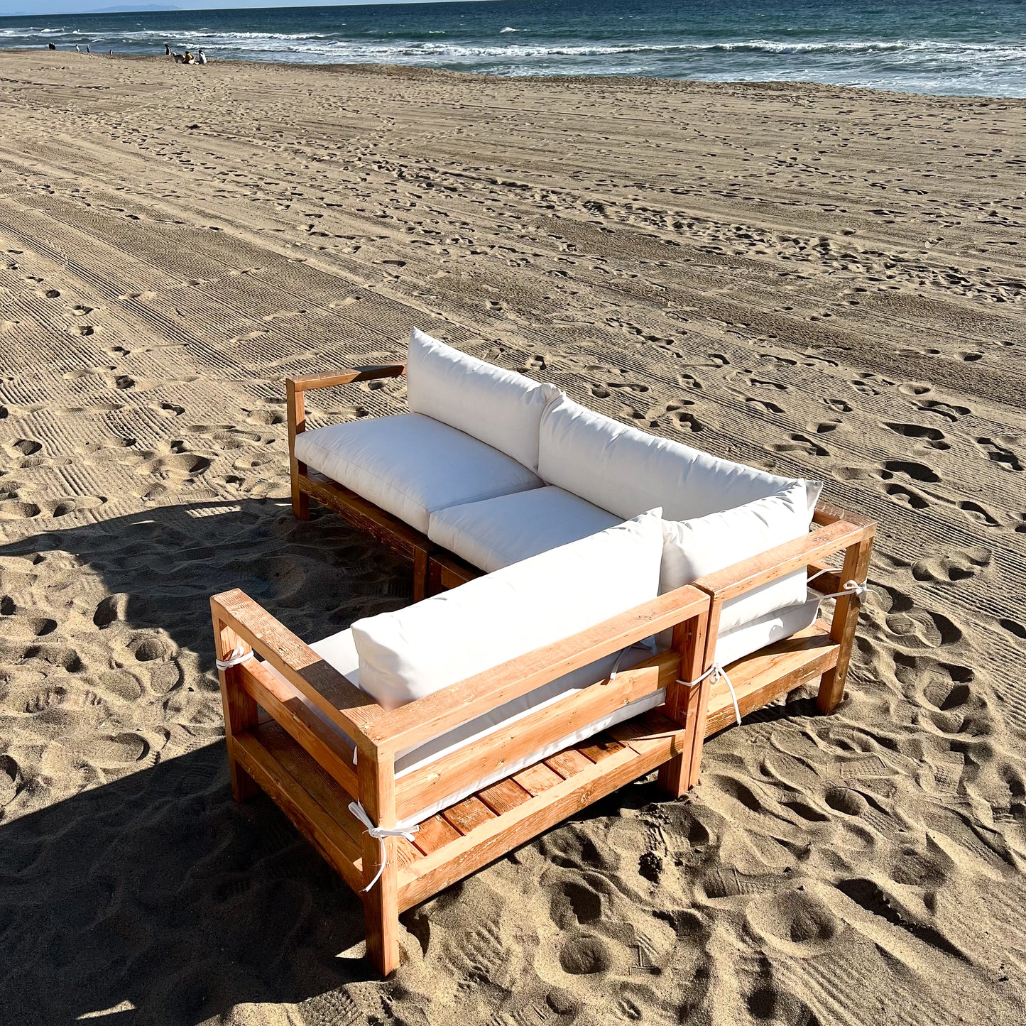 sectional sofa made of repurposed wood, off white cushions with outdoor fabric, medium brown wood color