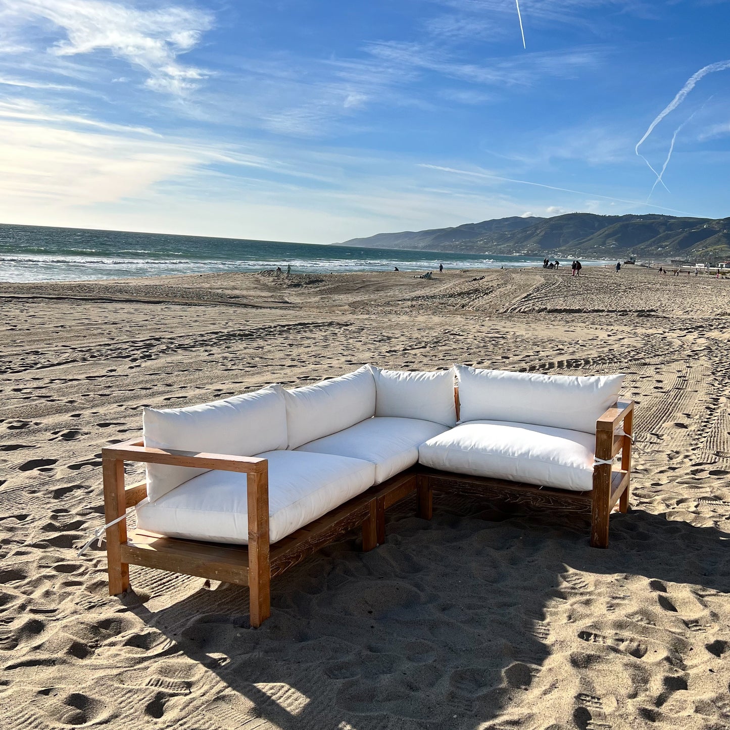 sectional sofa made of repurposed wood, off white cushions with outdoor fabric, medium brown wood color