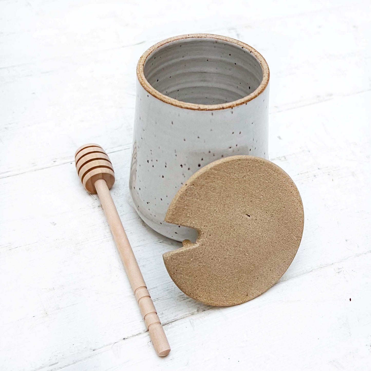 ceramic jar with lid and wooden honey dipper