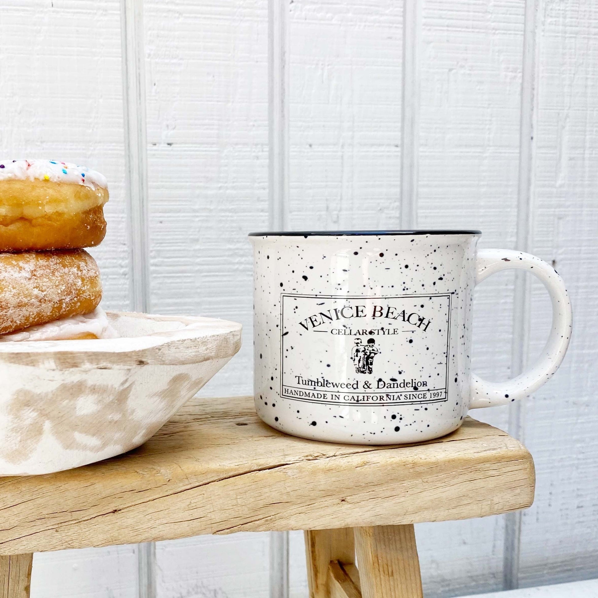 white enamel mug with black speckles and black Tumbleweed and Dandelion logo on front