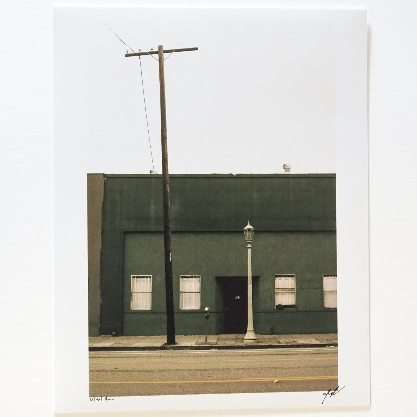 photograph of dark green building with streetlamp and telephone pole Edit alt text