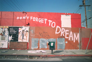 photograph of side of building that is painted red and brown with the words "don't forget to dream"