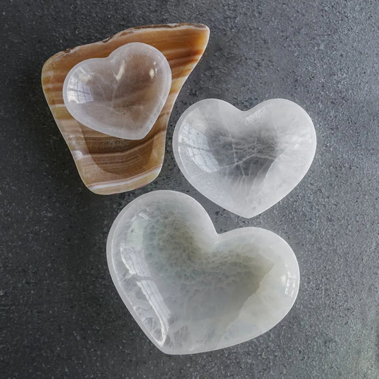 Three heart-shaped stones on a textured gray surface