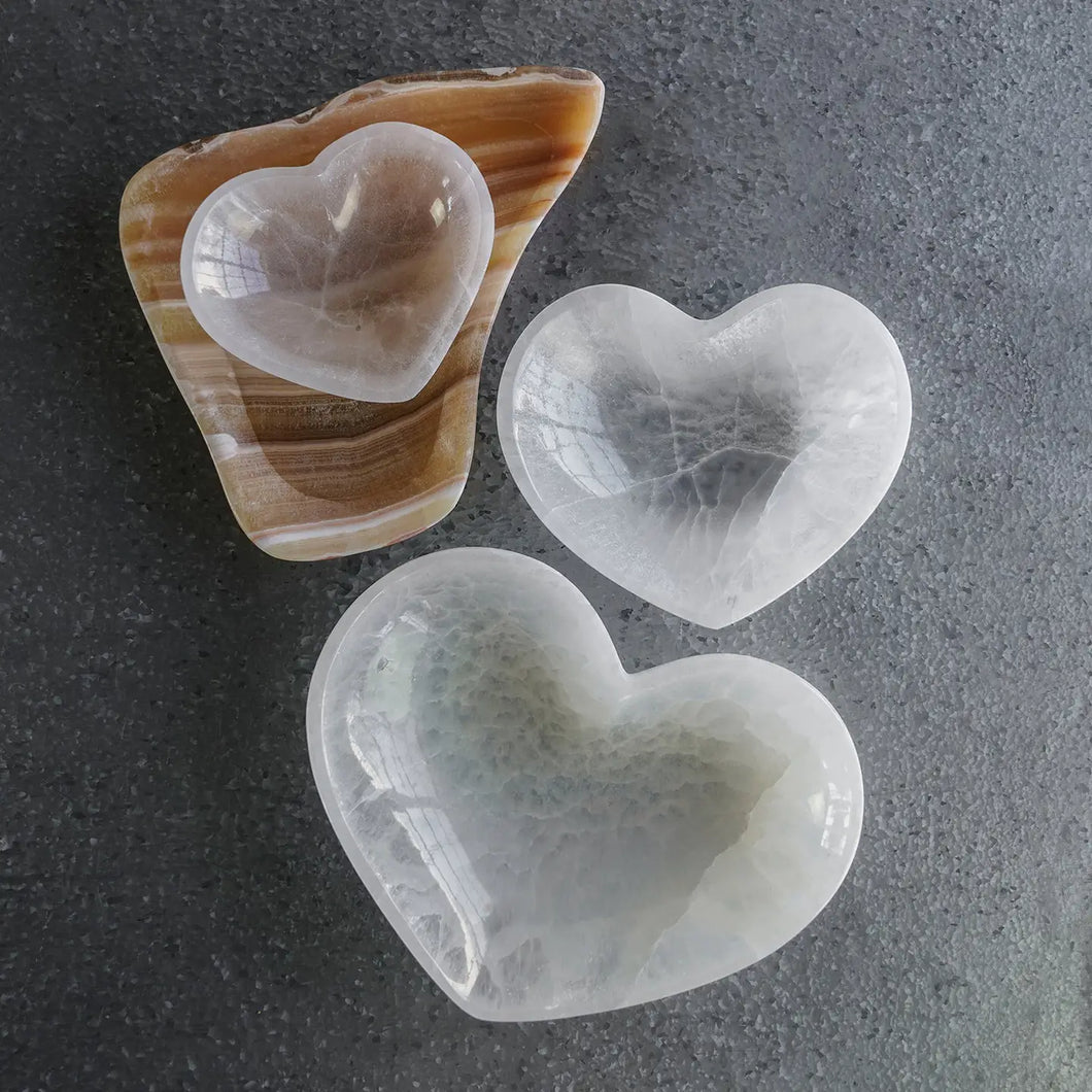Three heart-shaped stones on a textured gray surface
