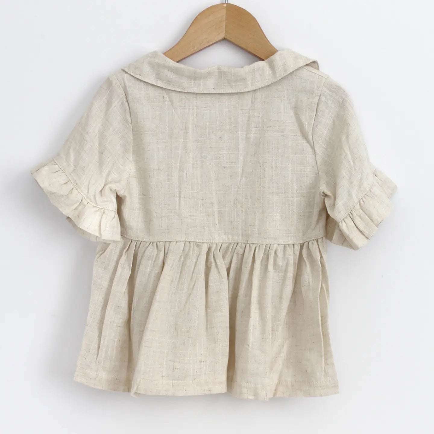 Beige blouse on a wooden hanger against a white background