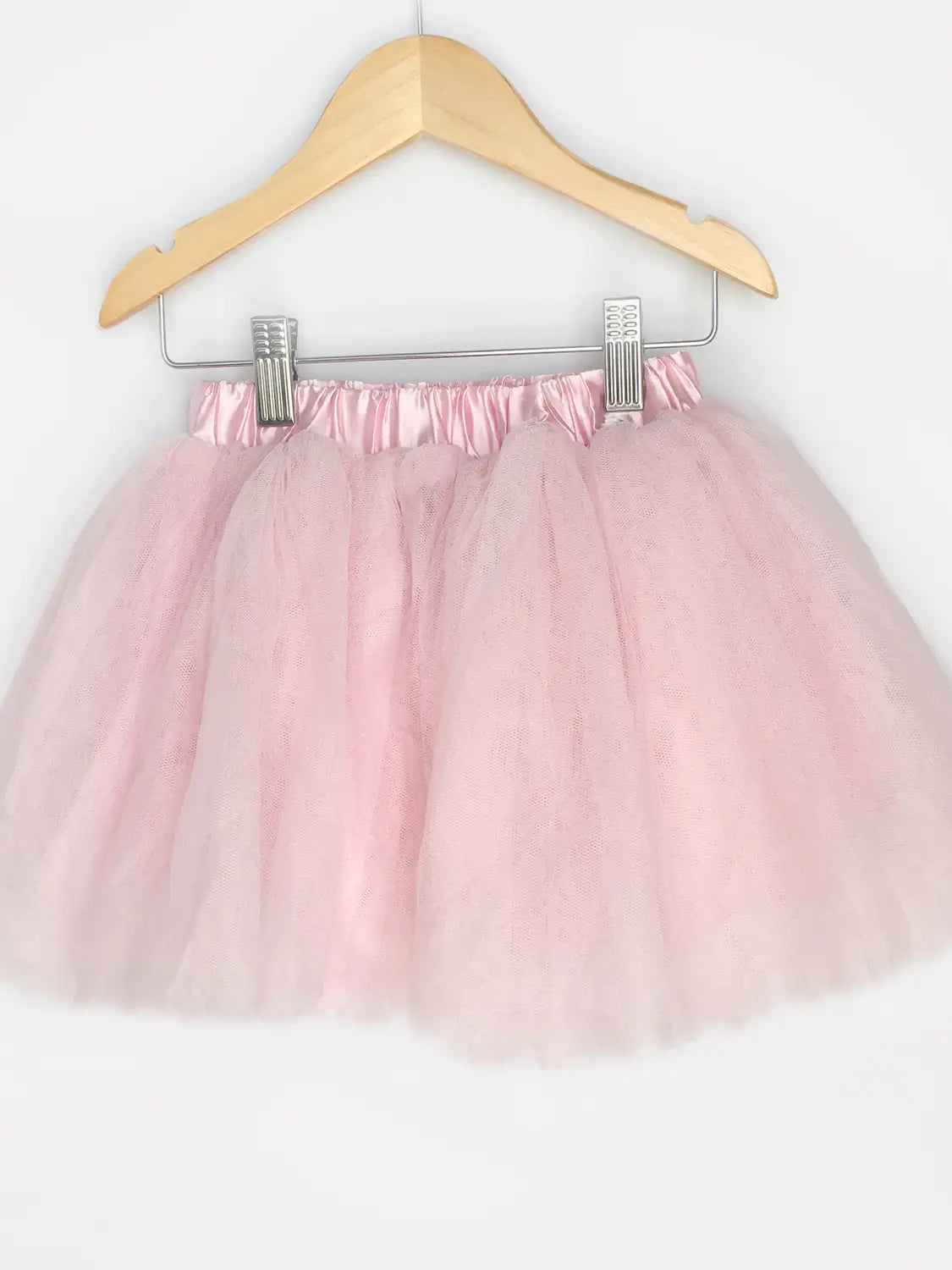 Pink tutu skirt on a hanger against a white background