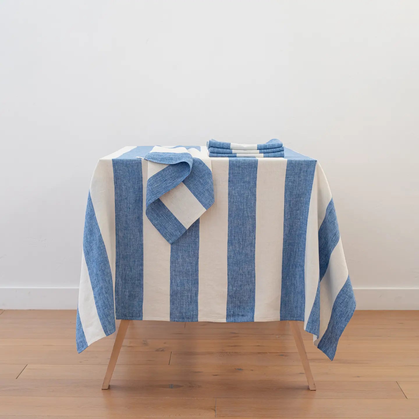 Blue and white striped towel on a wooden stool against a white wall