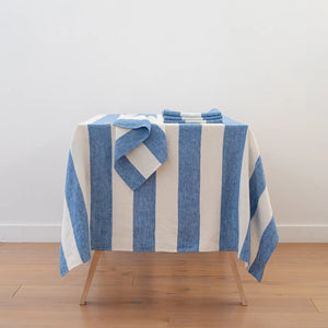 Blue and white striped towel on a wooden stool against a white wall