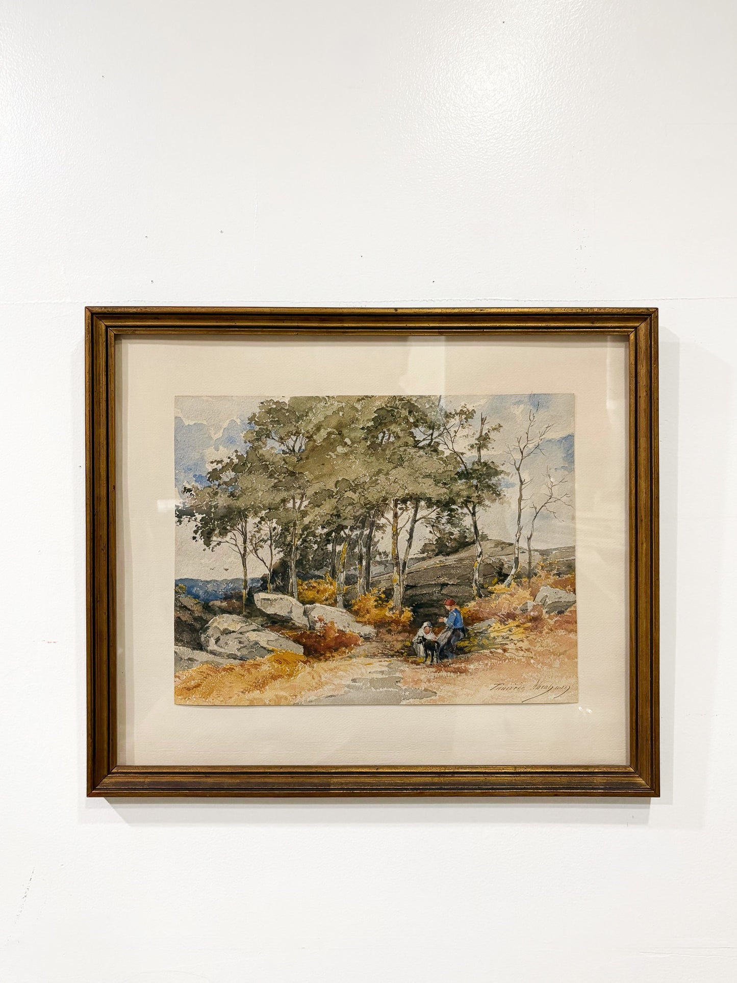 Framed artwork of a landscape with trees and a bench on a white wall
