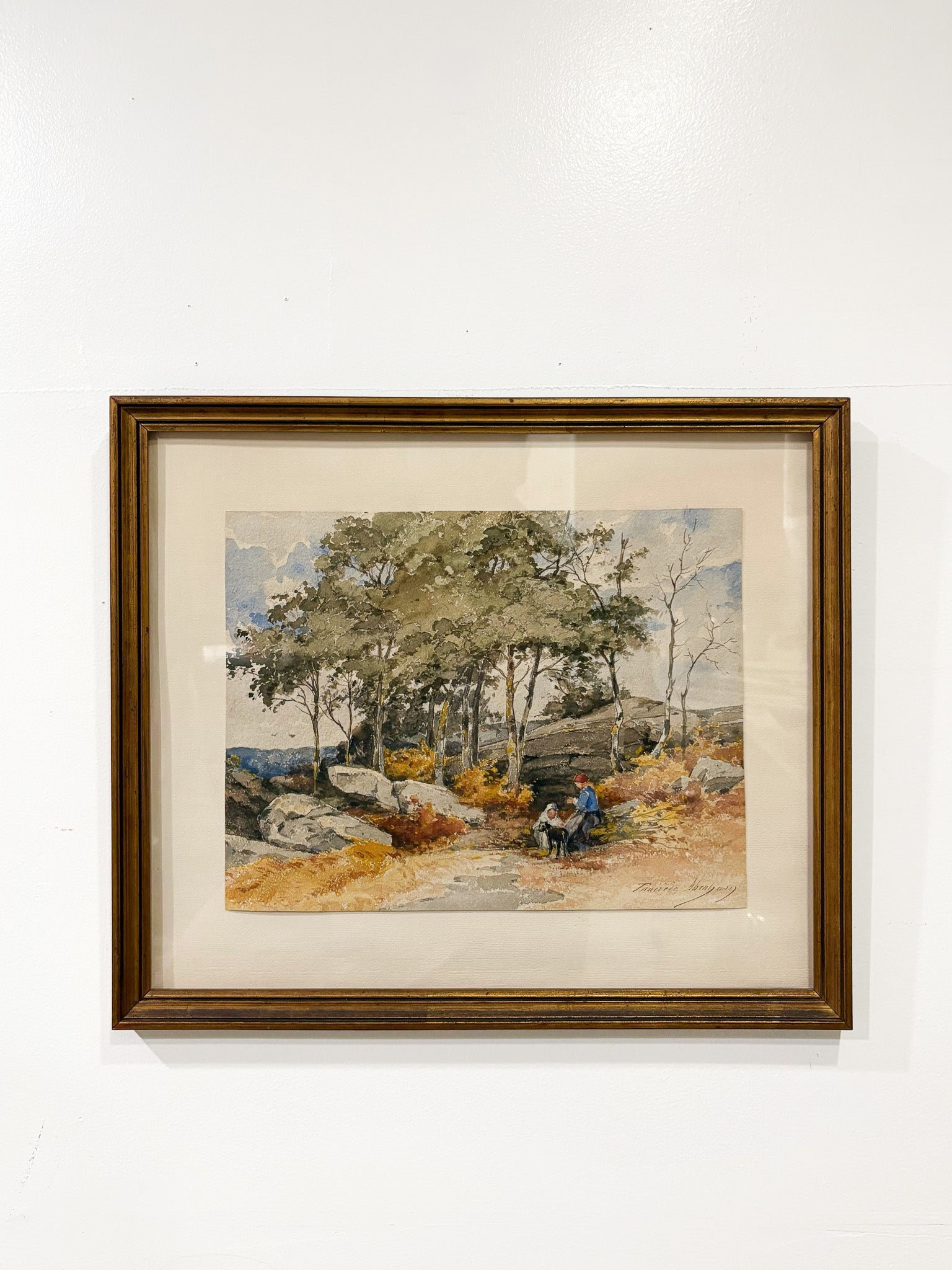 Framed artwork of a landscape with trees and a bench on a white wall