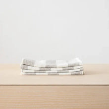 Load image into Gallery viewer, Stack of folded checkered towels on a beige surface with a light gray background