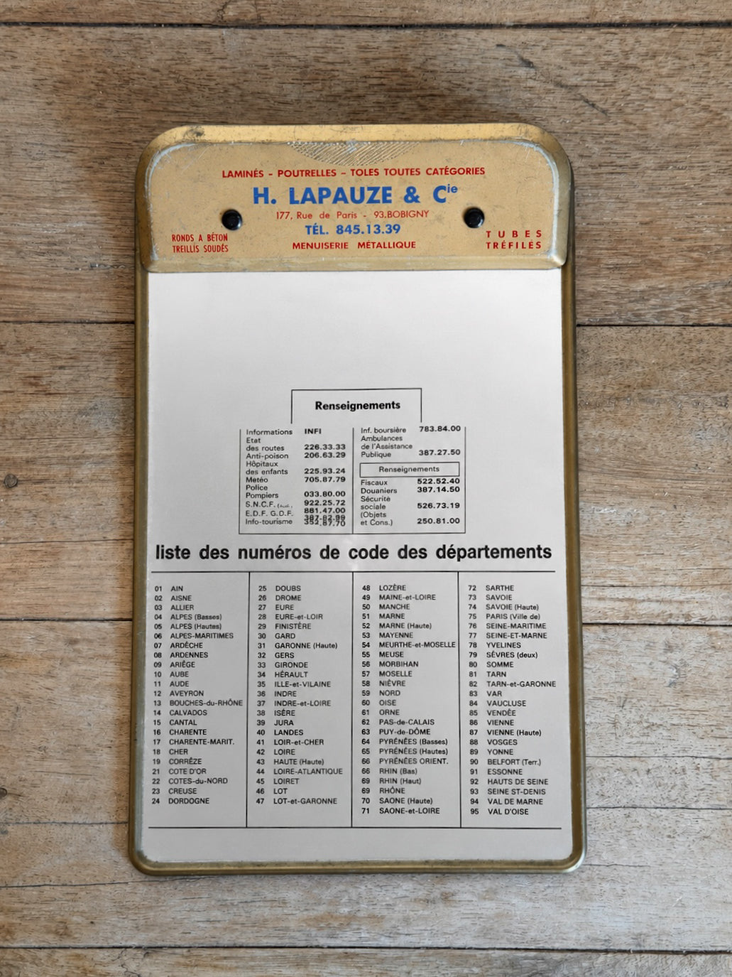Metal clipboard with text and numbers on a wooden surface