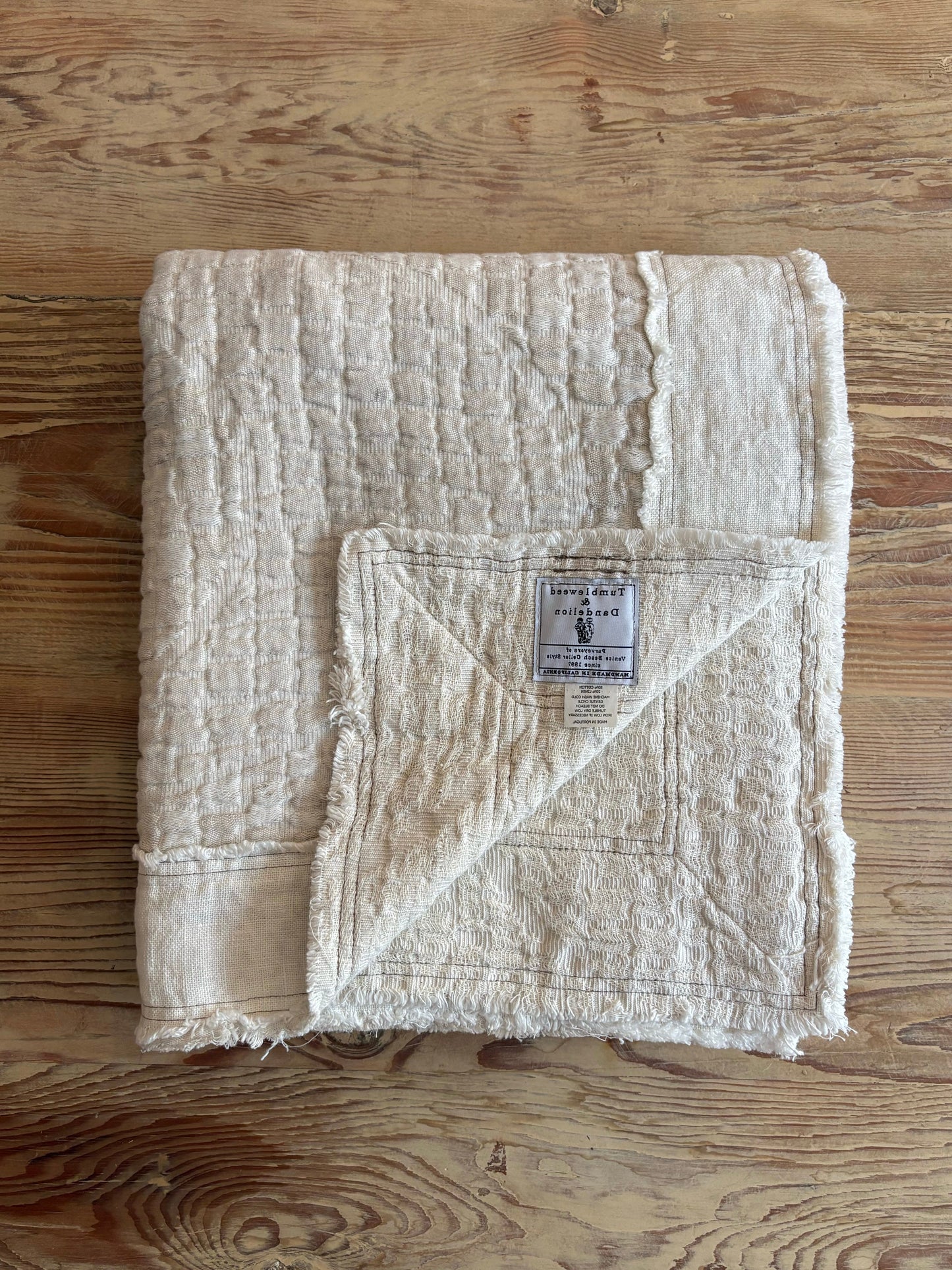 Folded beige fabric on a wooden surface with a visible label.