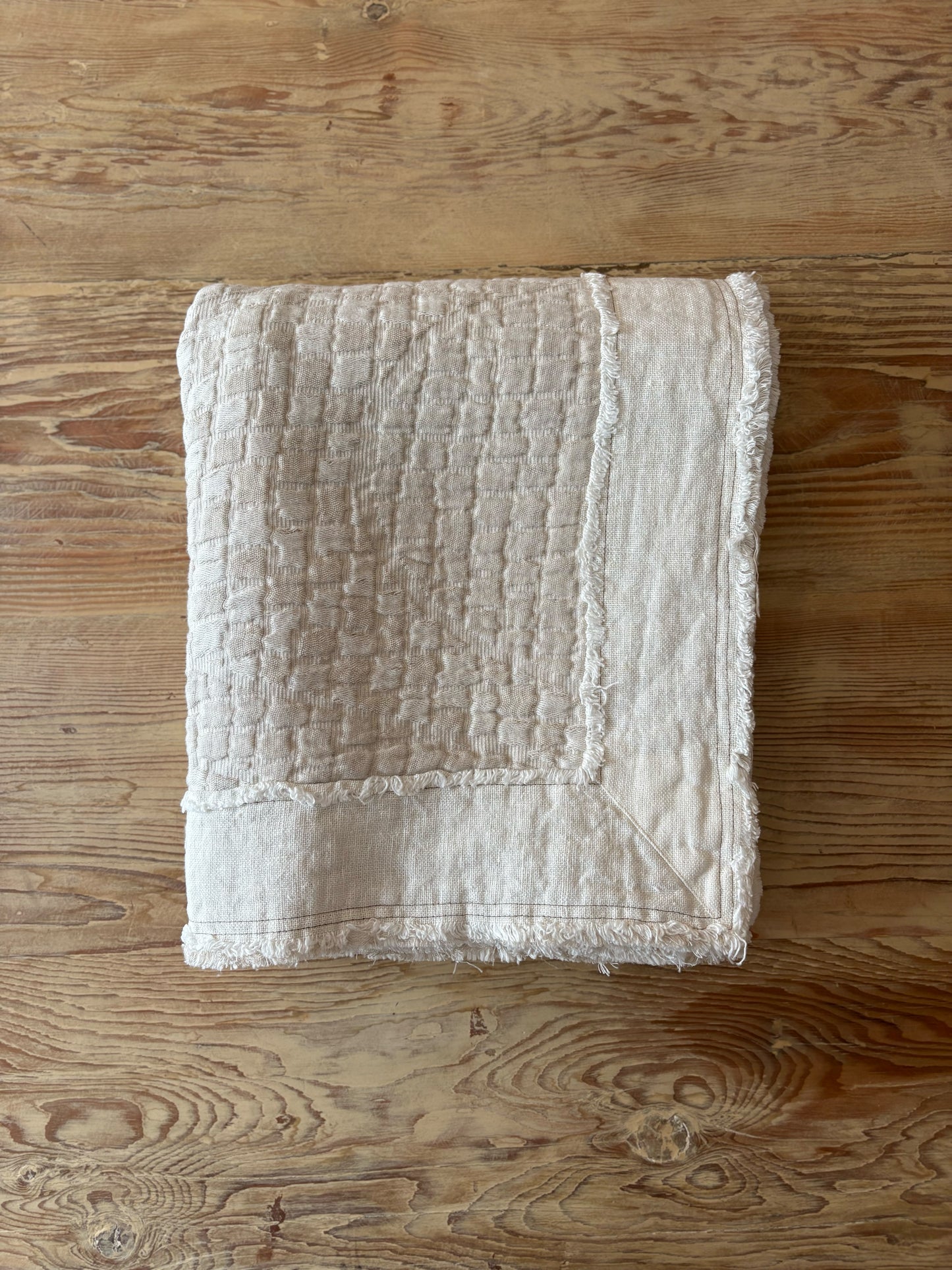 Textured beige blanket on a wooden surface