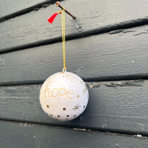 white paper mache round ornaments with gold decoration and word "hope"