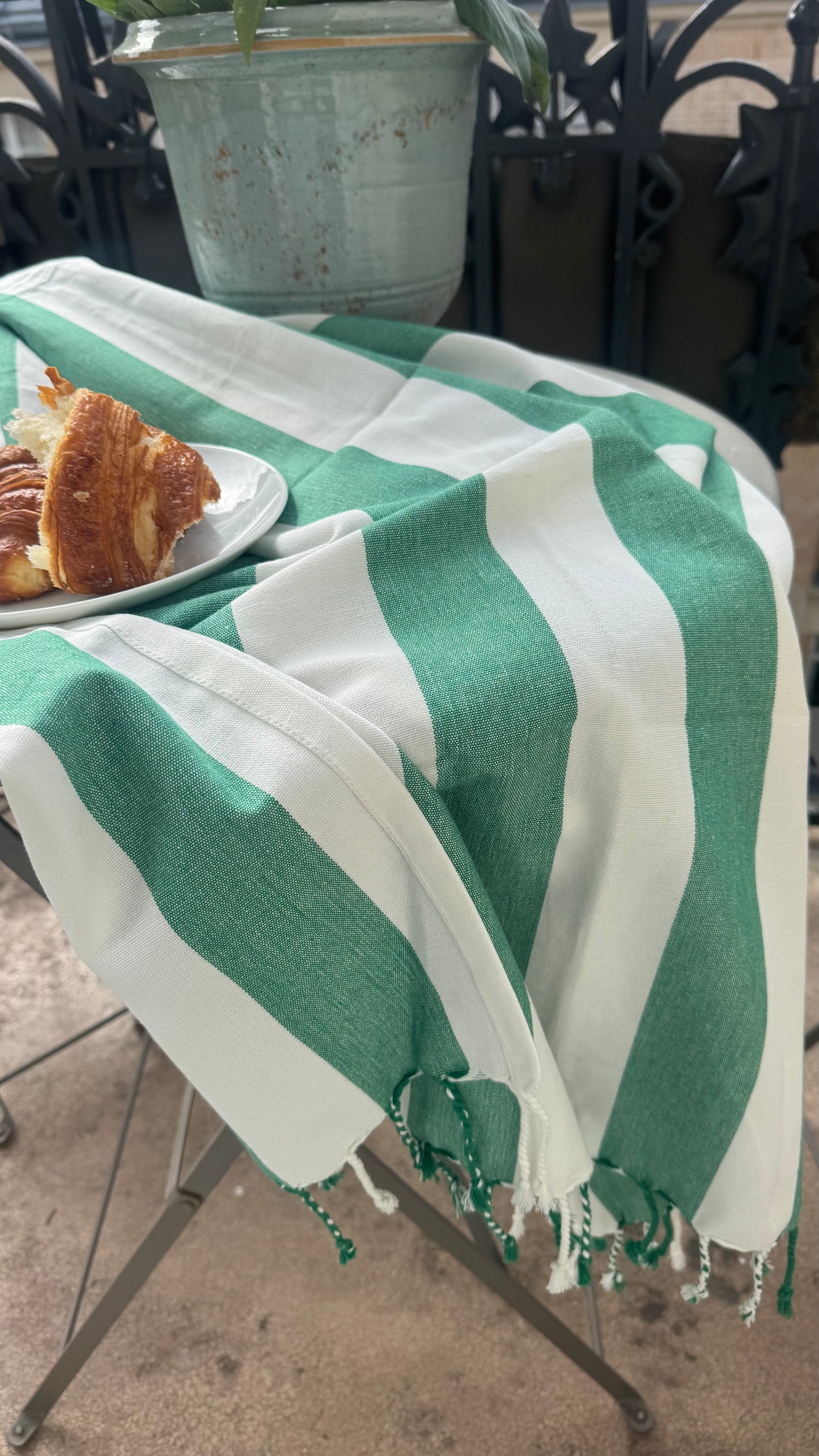 Green and white striped towel on a table with a plate of food in the background.