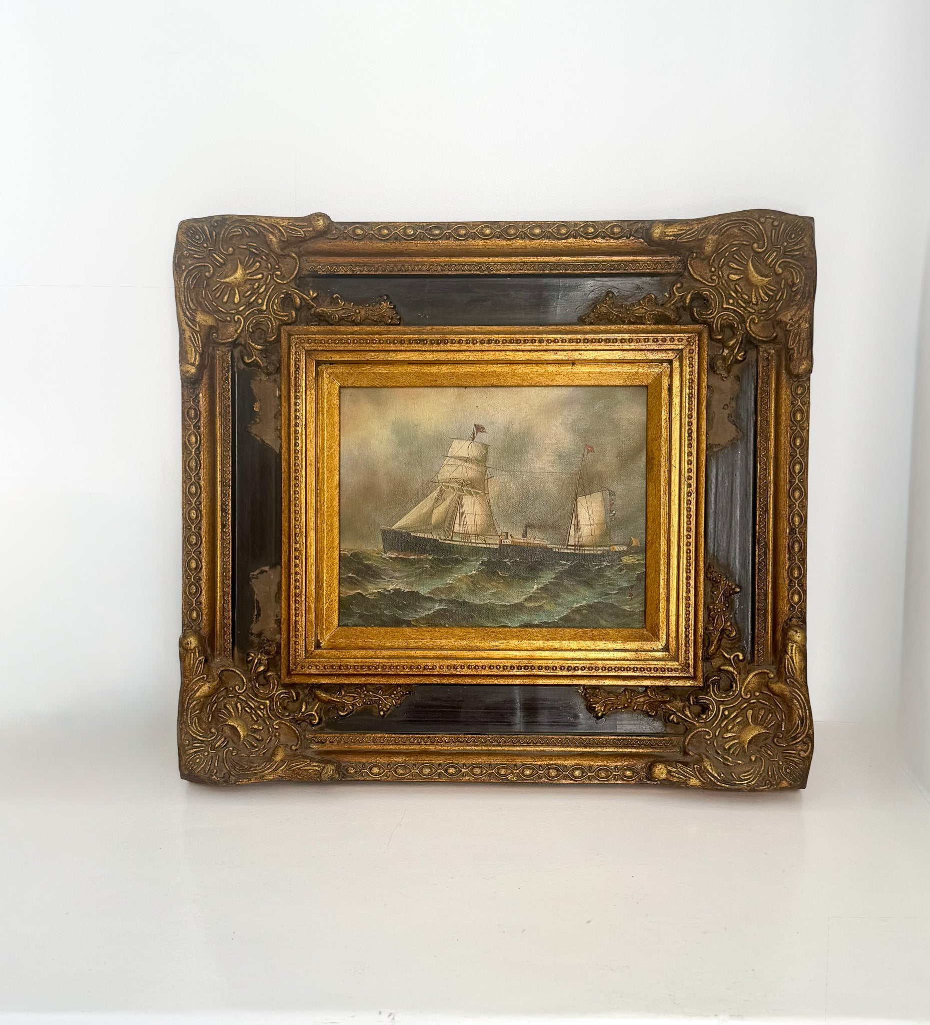 Decorative gold frame with a painting of ships on water