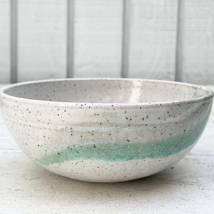 white ceramic bowl with brown speckles and green glaze accent