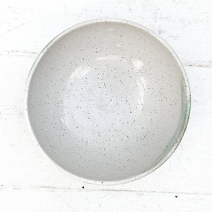 white ceramic bowl with brown speckles and green glaze accent