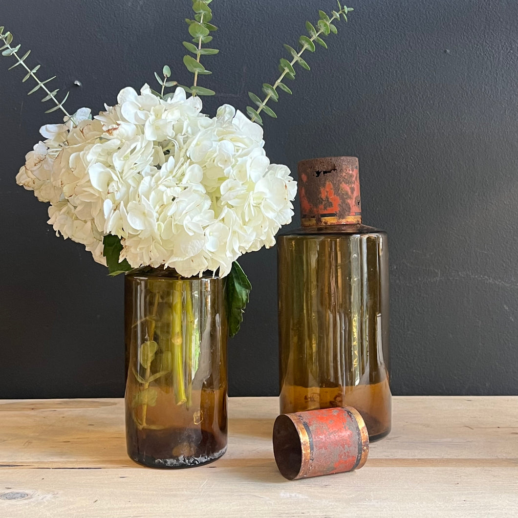 set of 2 vintage amber colored glass bottles with rusted red metal caps