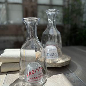 clear glass carafe with dome bottom that has French text in red and blue
