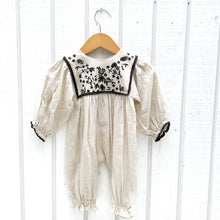 Load image into Gallery viewer, off white linen baby jumpsuit with black embroidery on chest and black trim on end of sleeves