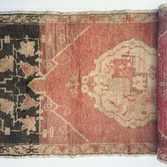 A vintage Turkish rug with floral patterns primarily in red and black colors.