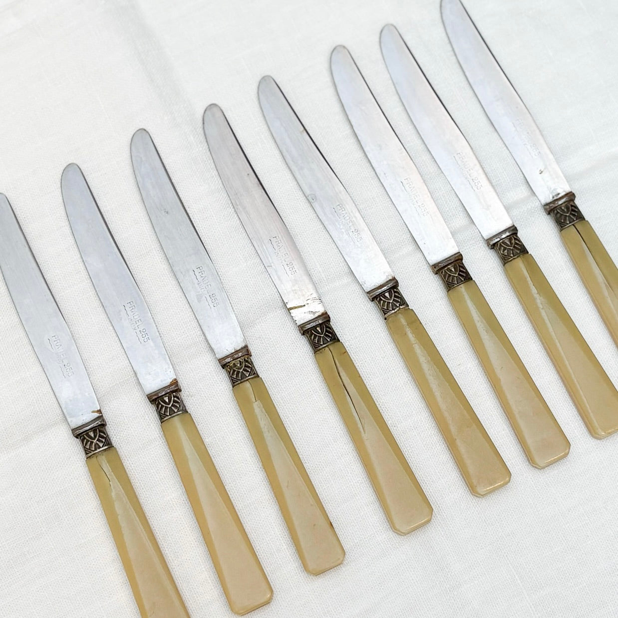 Set of eight knives with beige handles on a white background