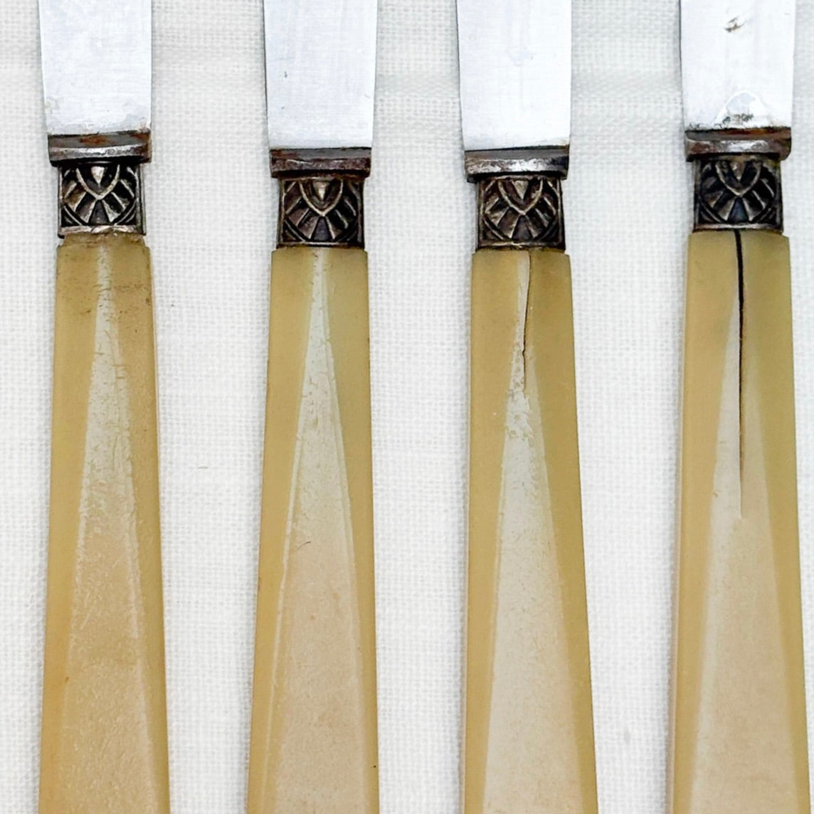 close up of Four vintage knives with beige handles on a white background
